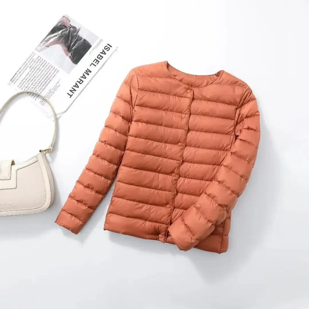 Terracotta quilted lightweight jacket laid flat beside a cream shoulder bag and a magazine