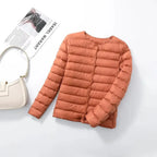 Terracotta quilted lightweight jacket laid flat beside a cream shoulder bag and a magazine