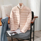 Pale pink quilted jacket with stand collar worn over a cream polo neck jumper on a chair