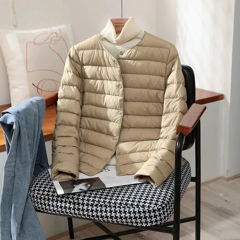 Khaki quilted lightweight jacket with stand collar styled over a cream polo neck jumper