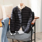 Black quilted lightweight jacket with stand collar hanging over a cream polo neck jumper