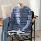 Haze blue quilted lightweight jacket with stand collar draped over a chair with denim