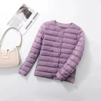 Light purple quilted lightweight jacket laid flat with a cream shoulder bag nearby