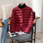 Burgundy quilted lightweight jacket with stand collar shown over a black polo neck jumper