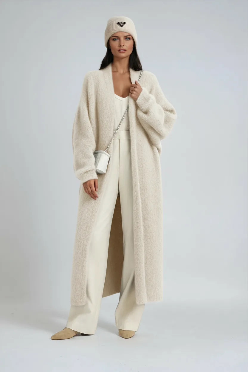 Front view of a woman in a cream textured long cardigan styled with wide cream trousers and a beanie