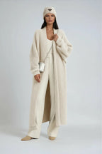 Front view of a woman in a cream textured long cardigan styled with wide cream trousers and a beanie