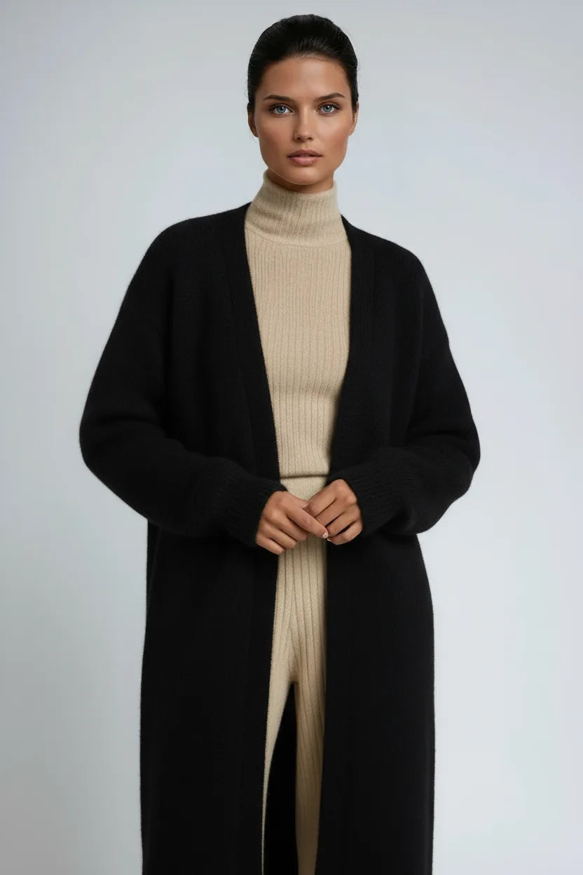 Close-up of a black long knit cardigan worn open over a beige ribbed polo neck jumper