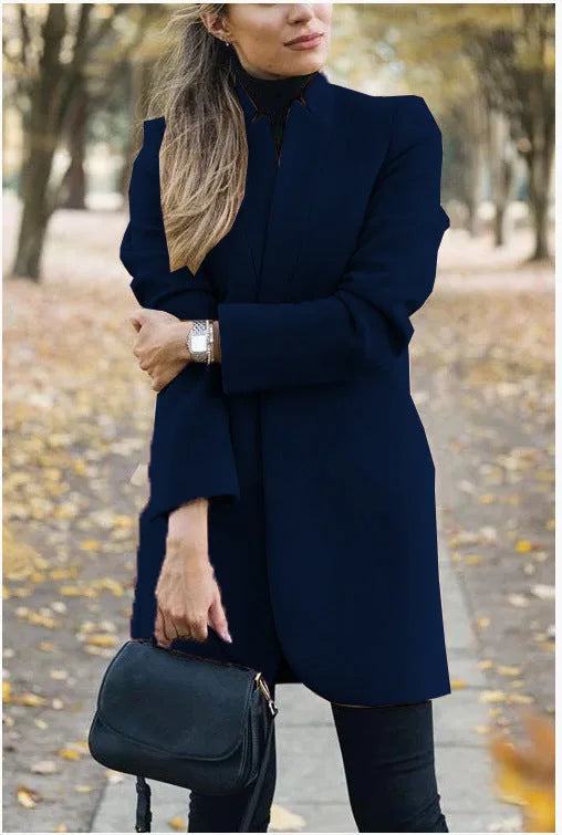 Navy blue longline blazer coat with stand collar worn open over a black polo neck and jeans