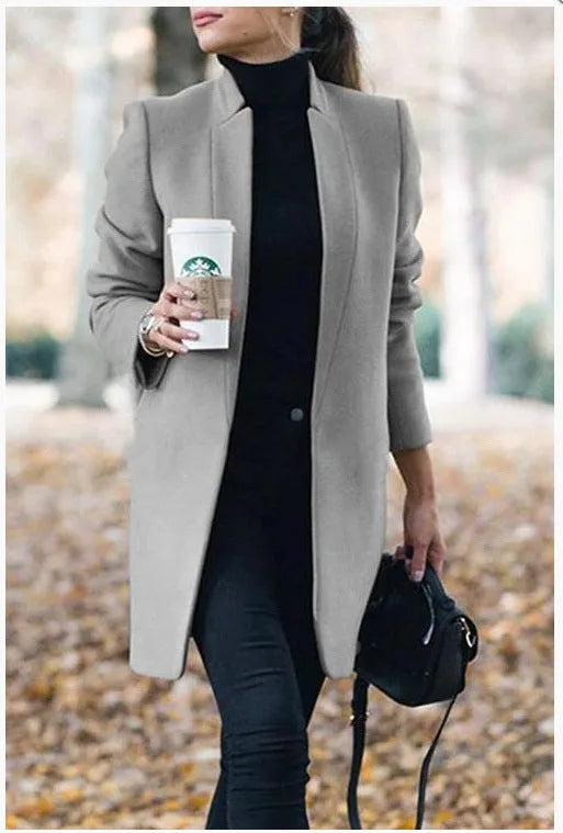 Grey stand collar longline blazer coat worn with a black polo neck and crossbody bag