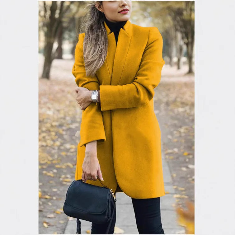 Mustard yellow longline blazer coat with stand collar and tailored fit worn with black trousers