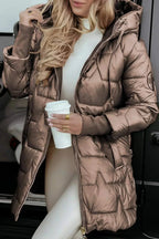 Woman in a bronze metallic puffer coat holding a coffee cup, hood up, zip open over a white jumper