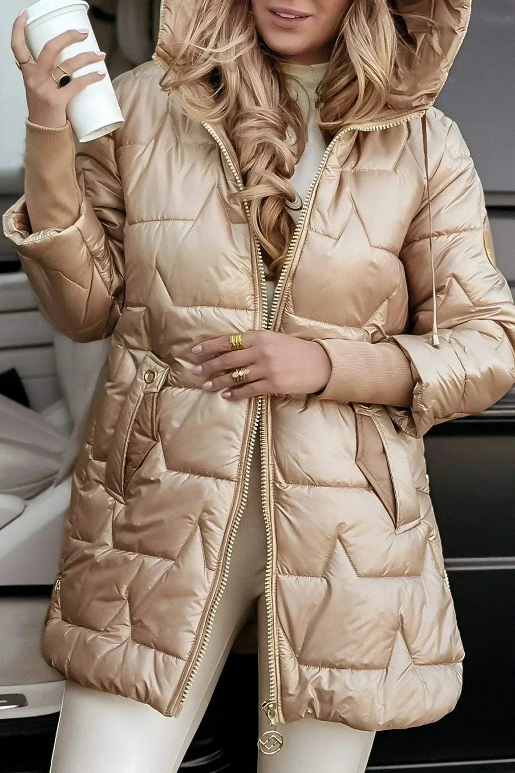 Side profile of the gold puffer coat showing the hood, sleeve patch logo and gold-tone zip pull