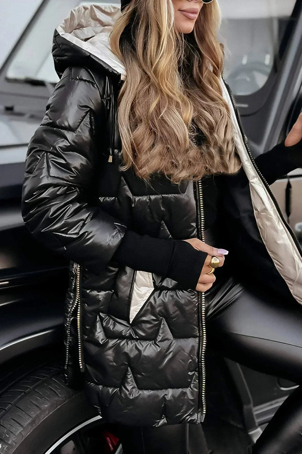 Close-up of the gold puffer coat's hood and sleeve badge, worn with a ribbed cuff jumper