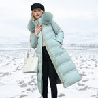 Woman adjusting the plush fur hood of a brown puffer coat while holding a smartphone