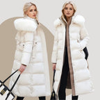 Woman walking outdoors in the black fur-hood puffer coat showing the coat's flowing maxi length