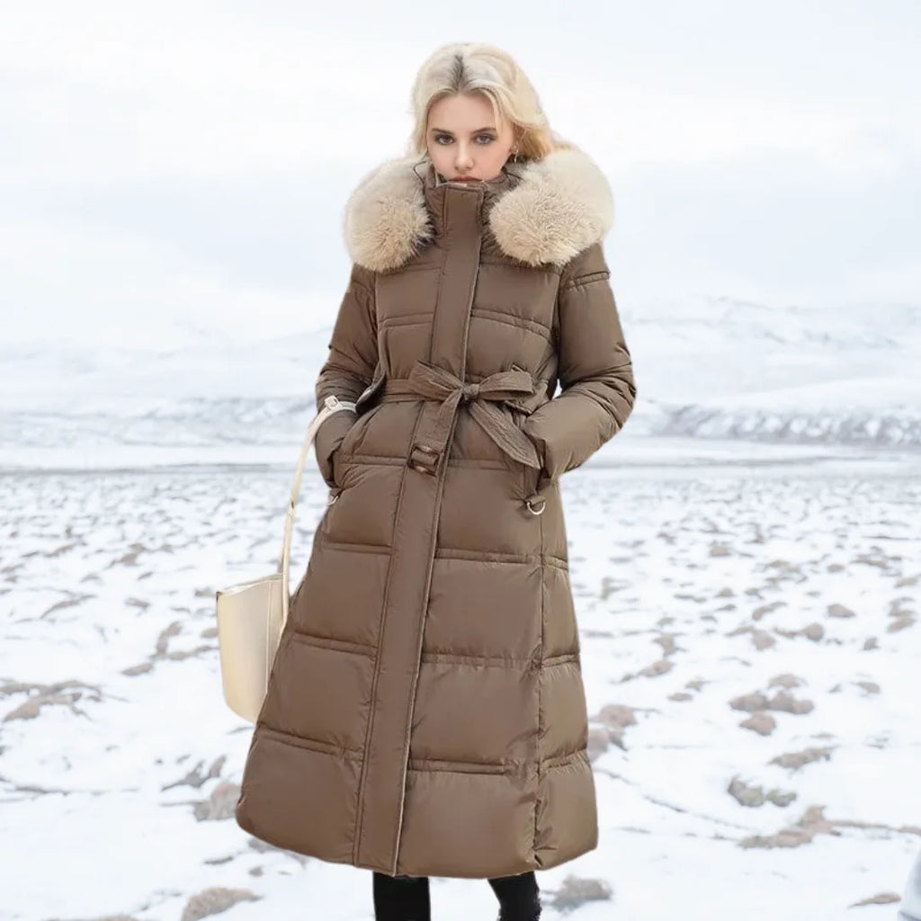 Front view of brown longline puffer coat with fur-trimmed hood and matching tie belt over black trousers