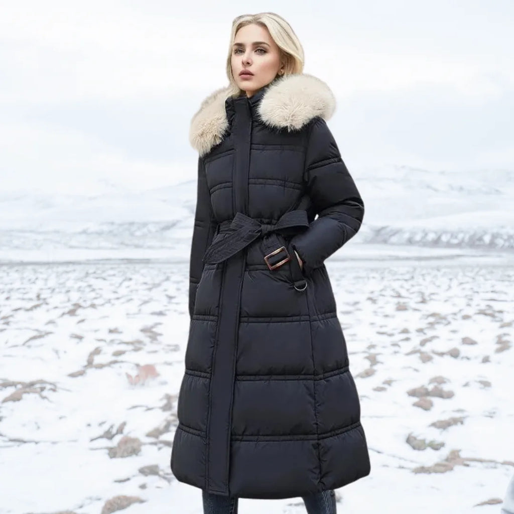 Woman in black puffer coat with cream fur hood and matching tie belt standing on a snowy field