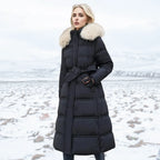 Woman in black puffer coat with cream fur hood and matching tie belt standing on a snowy field