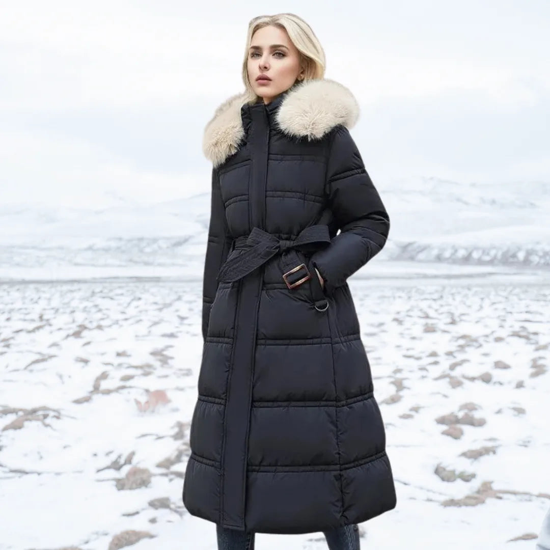Woman in black puffer coat with cream fur hood and matching tie belt standing on a snowy field