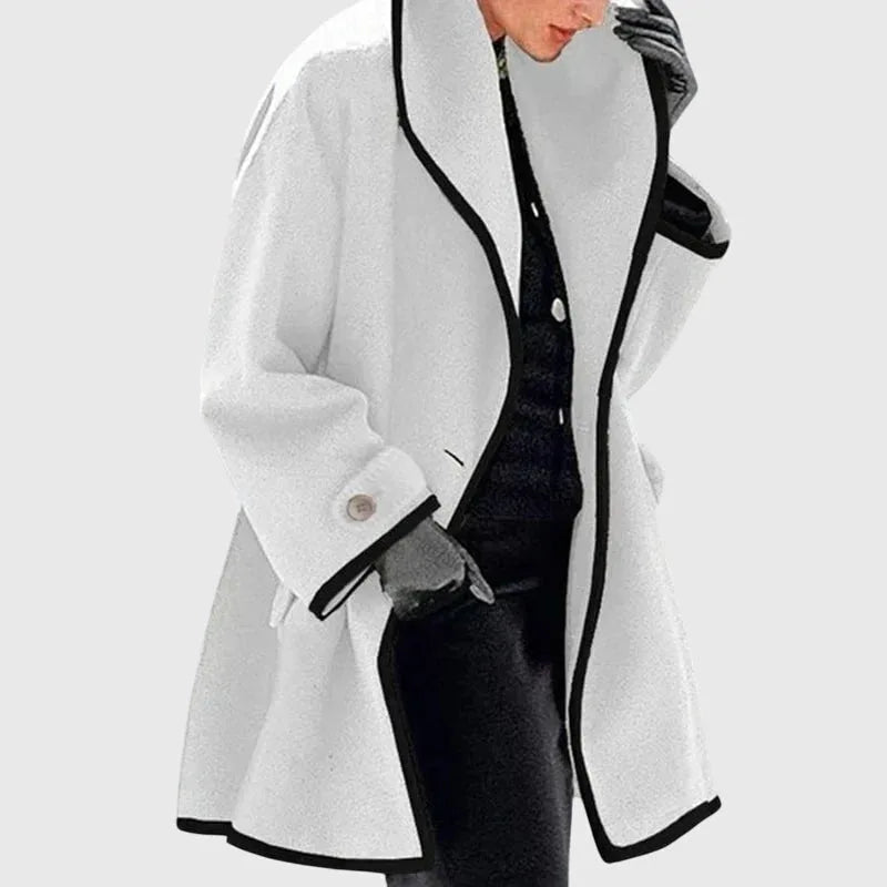 White longline tailored coat with black trim, oversized shawl collar and button cuff, worn open over dark layers
