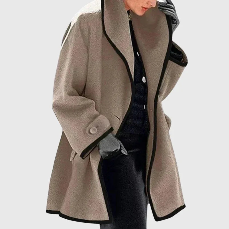 Beige longline coat with black contrast trim, relaxed silhouette layered over dark trousers