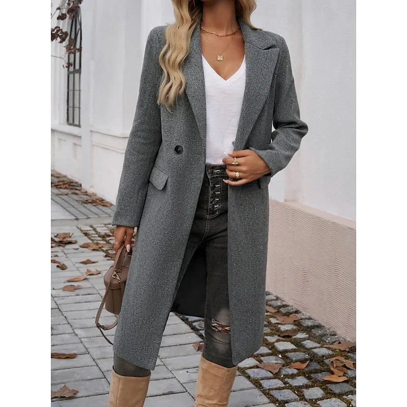 Woman wearing a longline dark grey tailored coat with turndown collar over a white top and jeans