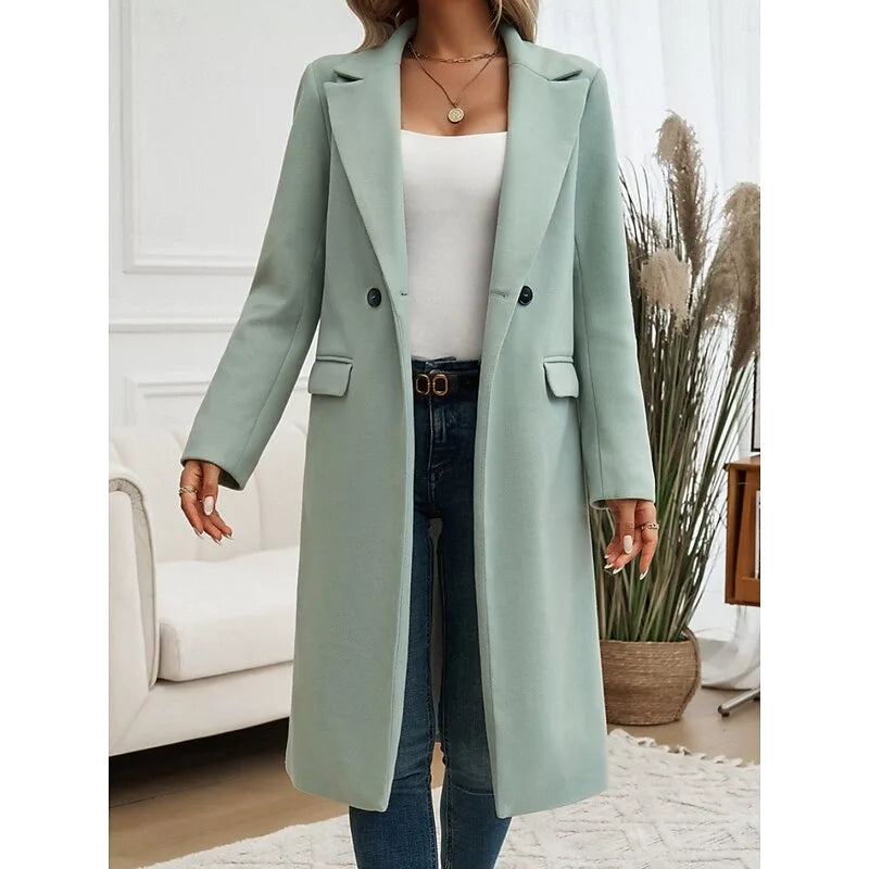 Sage green double-breasted longline coat worn buttoned with notched lapel over jeans and a white cami
