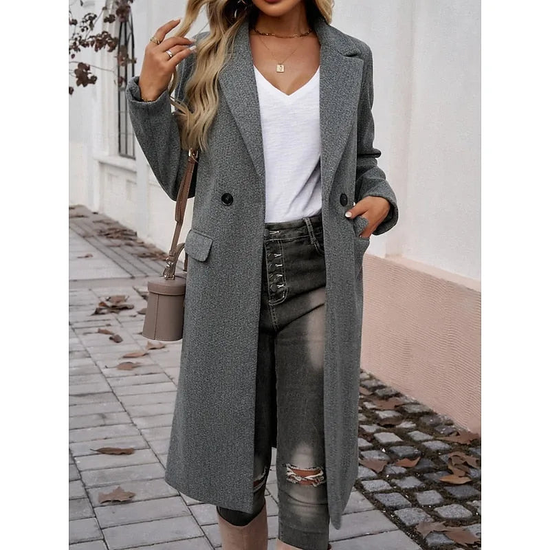 Close view of dark grey coat lapel and button detail with hand tucked into the front pocket