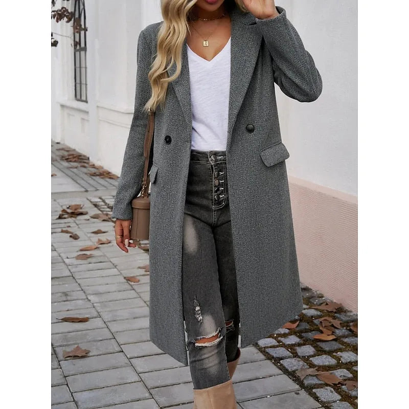 Dark grey longline coat worn open showing the front pocket flap and single button fastening