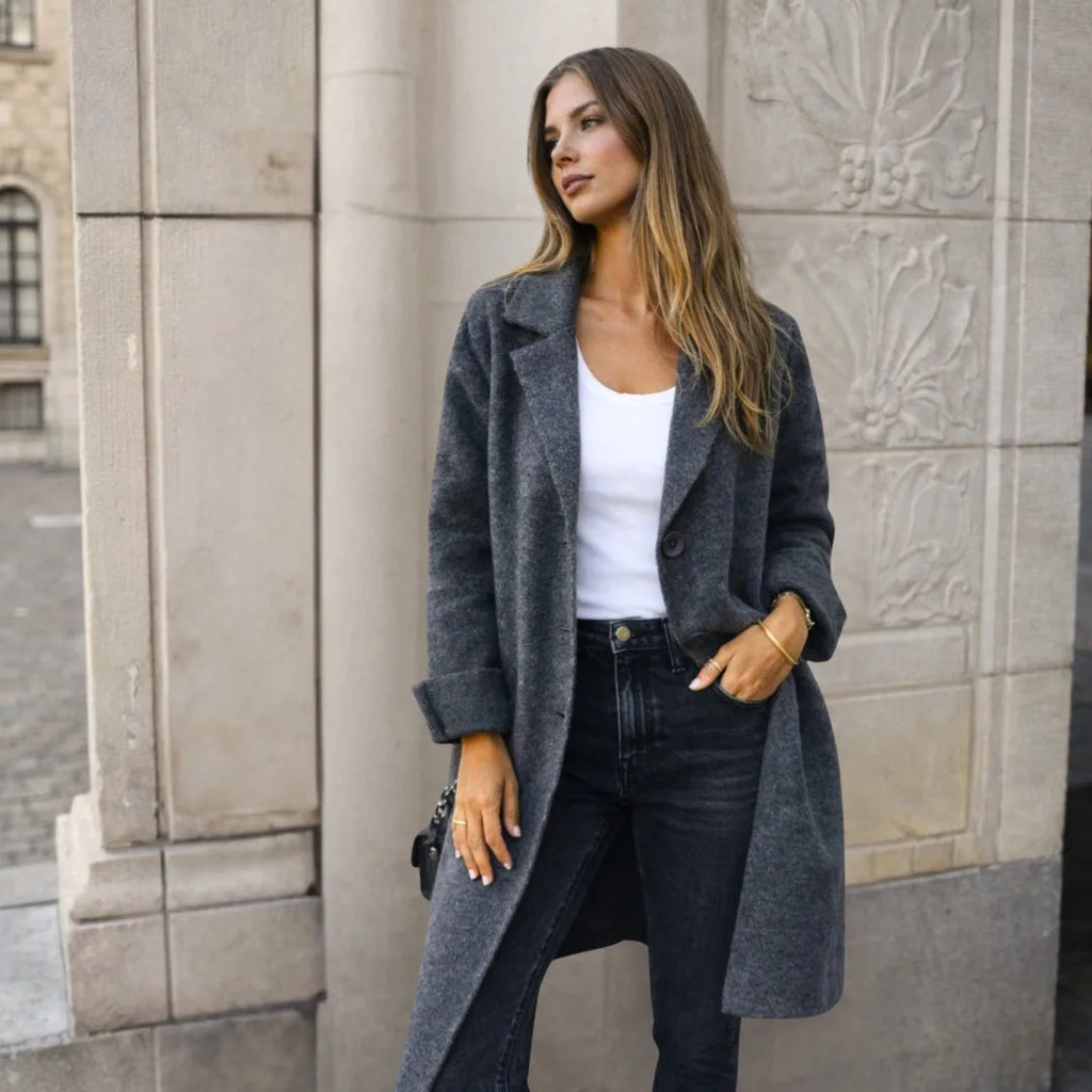 Side view of a mid grey longline wool coat with notch lapels and turned-back cuffs, worn open