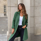 Model in a green longline wool coat buttoned at the waist, styled with a white top and black jeans