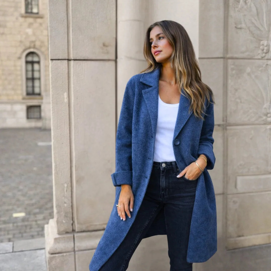 Close-up front view of a blue longline wool coat with structured lapels and a single button fastening