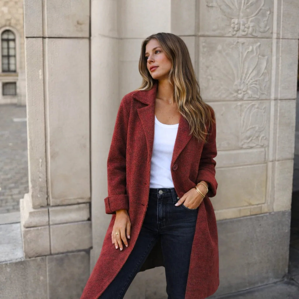Model wearing a rust red textured wool longline coat, hand in pocket, over black jeans