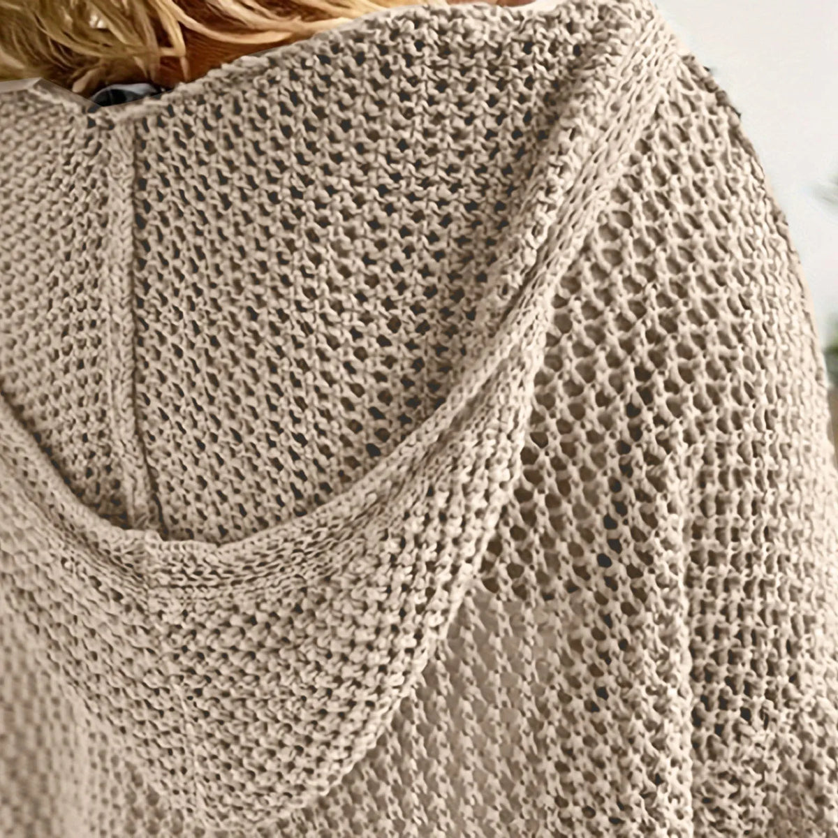 Close-up of the khaki open-knit fabric and hood seam, showing the chunky crochet-style stitch detail