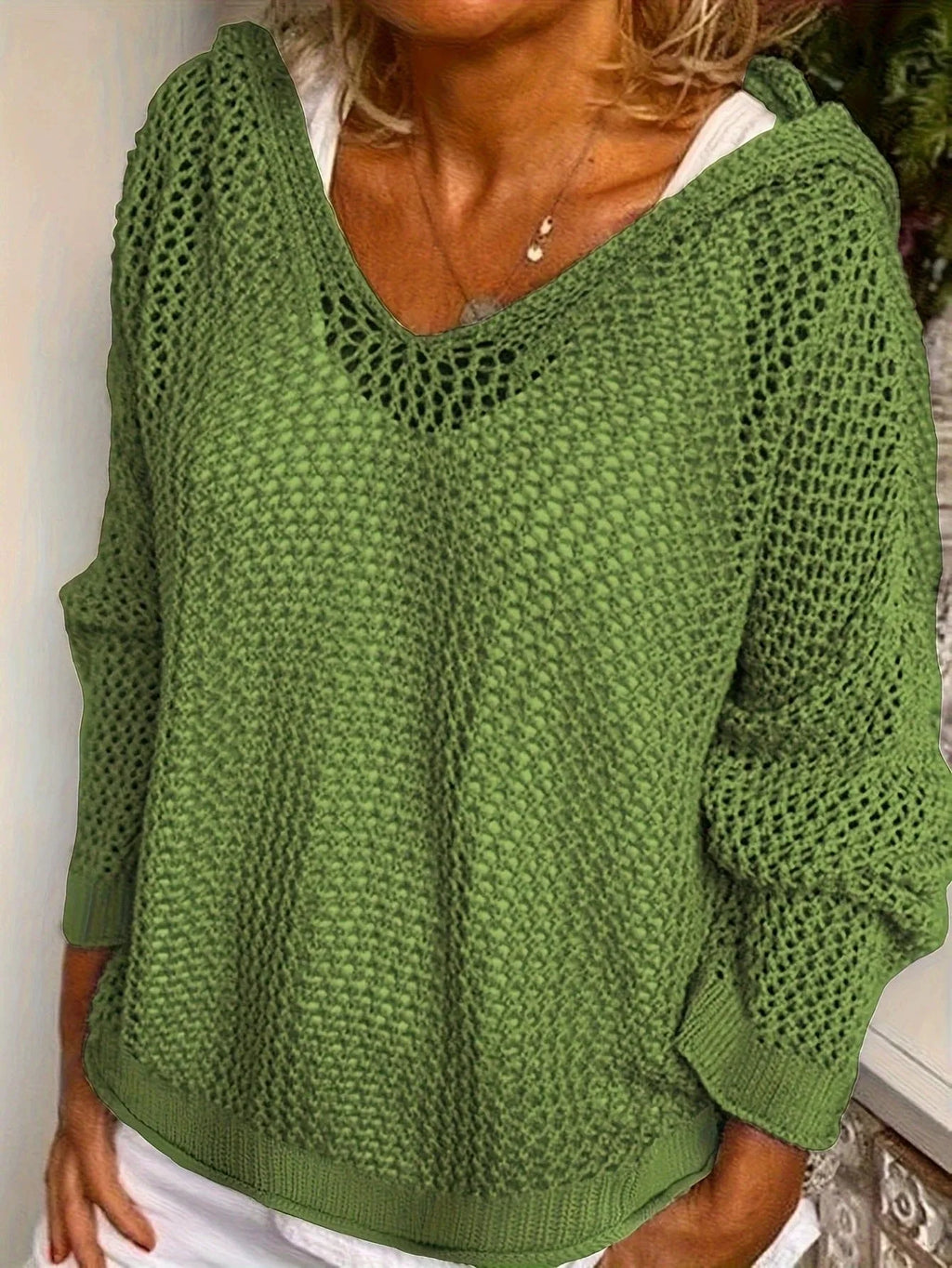 Model wears the green open-knit hooded jumper, close-up front view showing the V-neck and knit texture
