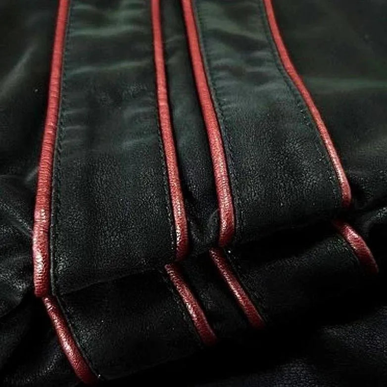 Close-up of the sleeve's layered red piping stripes stitched onto the black faux leather fabric