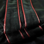 Close-up of the sleeve's layered red piping stripes stitched onto the black faux leather fabric