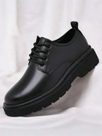 Angled close-up of a single black leather derby shoe showing lace-up front, round toe and chunky ridged sole.