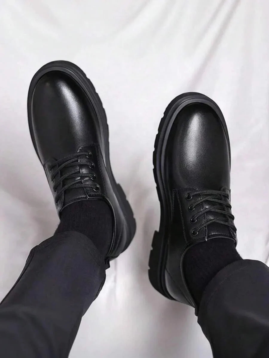 Top-down view of both black leather derby shoes side by side, highlighting the round toe and eyelet lacing detail.