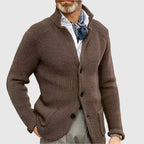 Man wearing the olive green cardigan outdoors with grey trousers and a wristwatch