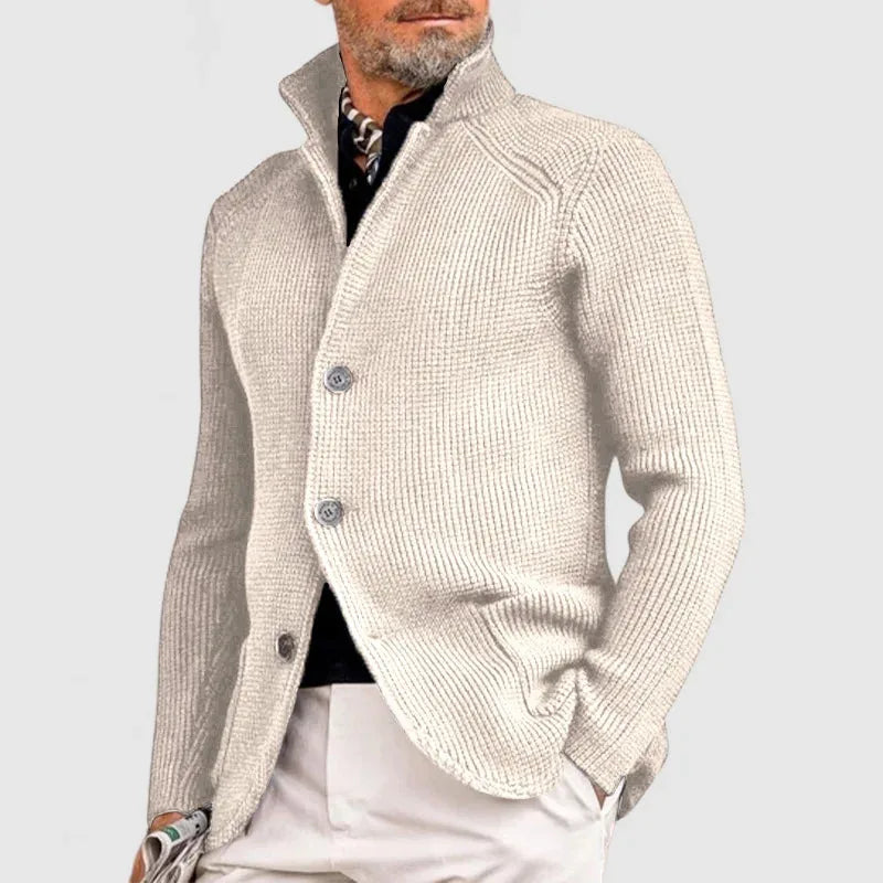 Beige ribbed knit button-front cardigan with stand collar worn over a dark polo neck