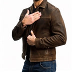 Side angle of brown leather jacket with sleeve cuff and chest pocket detail, hand resting on chest