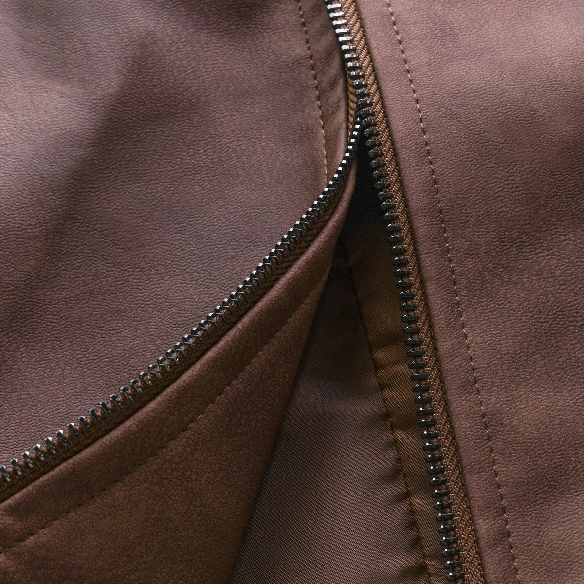 Close-up of open zip fastener showing brown leather exterior and soft inner lining