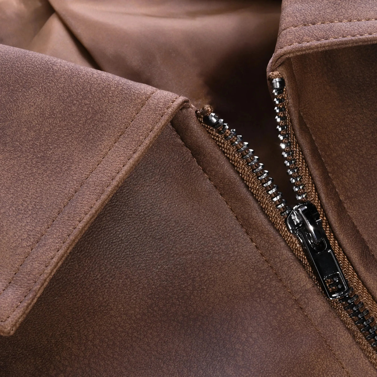 Close-up of collar and zip pull detail on brown leather jacket showing stitching and hardware