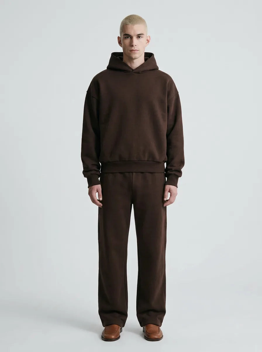 Man wearing a dark brown hooded sweatshirt and matching joggers paired with tan leather shoes