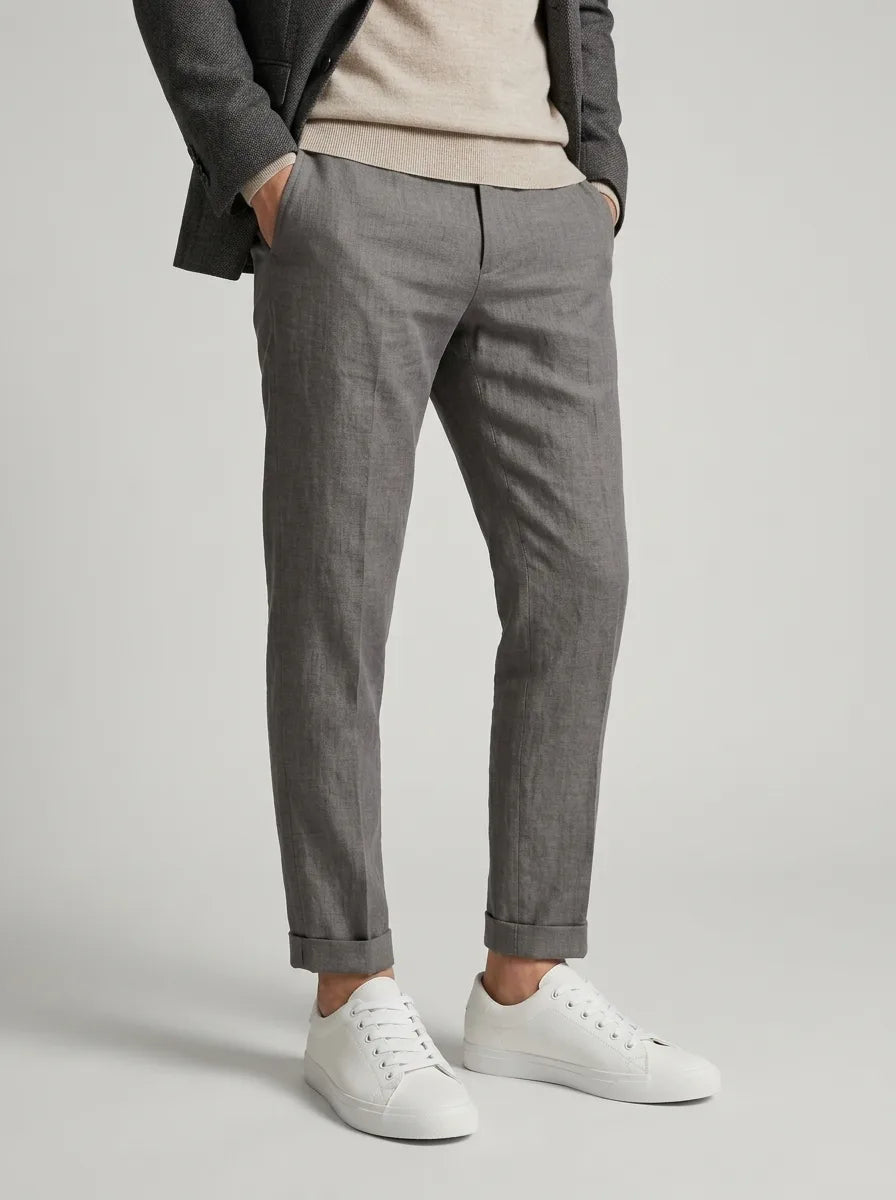 Man styled in grey trousers rolled at the ankle, worn with white trainers