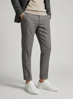 Man styled in grey trousers rolled at the ankle, worn with white trainers