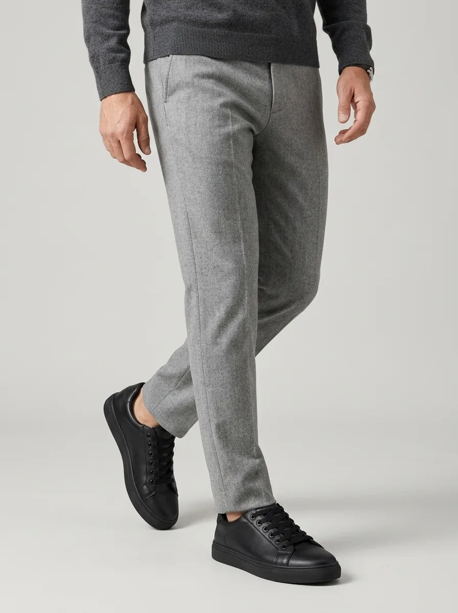 Close-up side view of black trainers paired with slim grey flannel trousers