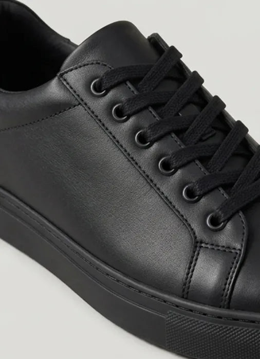 Close-up of the lace-up front and smooth upper of a black trainer