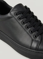 Close-up of the lace-up front and smooth upper of a black trainer